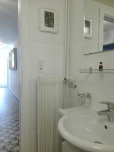 a white bathroom with a sink and a radiator at "Le Sorelle" Apartments in Ferden