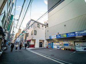 a group of people walking down a street between buildings at Stay Osaka Namba in Osaka