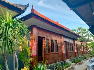 a house in a resort with trees in front of it at Nusa Garden Homestay in Nusa Lembongan