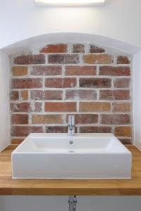 a white sink in front of a brick wall at einzigartig - Das kleine Hotel im Wasserviertel in Lüneburg