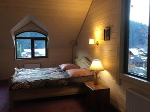 a bedroom with a bed with a lamp and a window at Вілла Лісова комфорт in Skhidnitsa