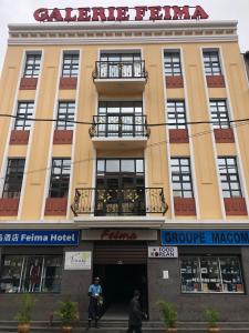 Feima Hotel في أنتاناناريفو: مبنى اصفر كبير فيه ناس تمشي امامه