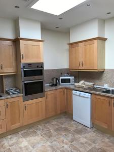 a kitchen with wooden cabinets and white appliances at Thurdistoft Farmhouse, Dunnetbay accommodation in Thurso