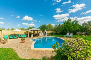 a swimming pool in a yard with chairs and umbrellas at Casa Baix in Sineu