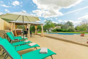 a patio with chairs and an umbrella and a pool at Casa Baix in Sineu