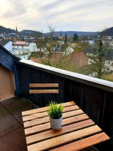 a wooden bench on a balcony with a potted plant at Wohlfühl-Apartment Bad Kissingen IV in Bad Kissingen