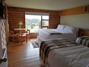 a bedroom with two beds and a table and a window at Casa Bosque Chiloé in Dalcahue