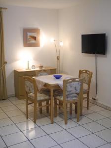mesa de comedor con sillas y TV en Ferienwohnung Heinen, en Andernach