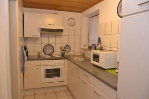 a small kitchen with white cabinets and a microwave at Ferienwohnung Heinen in Andernach
