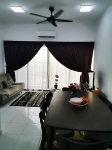 ein Wohnzimmer mit einem Tisch und einem Deckenventilator in der Unterkunft Yunne Homestay in Sepang