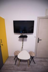 a room with a tv and a table and two stools at Hostel Evropa in Nikšić