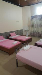 3 camas en una habitación con sábanas rosas en Wli Water Heights Hotel, en Wli Afegame