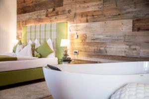un bagno con vasca e una camera con letto di Hotel Garnì Laurino a Cavalese