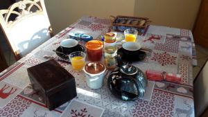 una mesa con un mantel con zumo de naranja y un hervidor de agua. en Chambre d'hôtes - La Maurillonnette en Saint-Pancrace