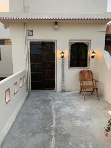 una sedia seduta davanti a una casa con una porta di Jaipur Haveli a Jaipur