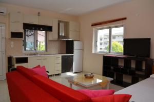 a living room with a red couch and a kitchen at Gregory's Apartments in Ksamil
