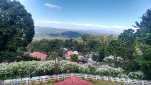 a town with a white fence and mountains in the background at Velu's Resort in Gūdalūr