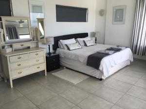 a bedroom with a bed and a dresser and a mirror at Dream a Little in Simonʼs Town