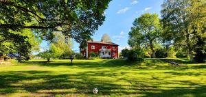 a red house in the middle of a green field at Sunnemoslantliv B&B in Sunnemo