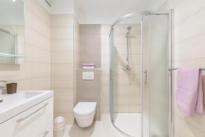 a white bathroom with a shower and a toilet at Apartments Kadenca in Omiš +82 photos