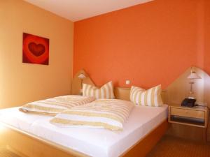 uma cama num quarto com uma parede laranja em Haus Talblick em Willingen