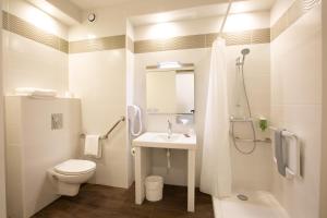 a white bathroom with a toilet and a sink at Hotel Chantereyne in Cherbourg en Cotentin