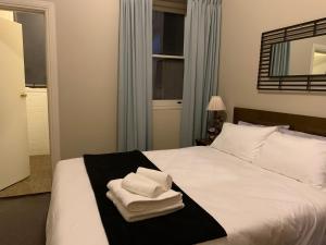 - une chambre avec un lit et des serviettes dans l'établissement Boutique Apartment in The Heart of Adelaide CBD, à Adélaïde