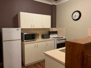 a kitchen with a refrigerator and a clock on the wall at Boutique Apartment in The Heart of Adelaide CBD in Adelaide