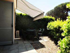 a patio with a table and chairs under awning at Monolocale con giardino a 100m dal mare Punta Ala in Punta Ala