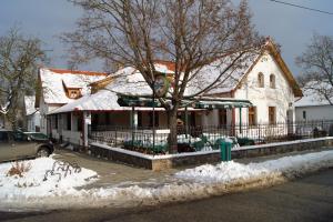 a building with snow on the ground in front of it at Rácz Fogadó in Kisoroszi