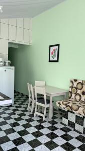 a kitchen with a table and chairs on a checkered floor at Casa, 1 quadra da praia. in Ilha Comprida