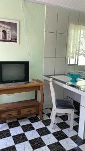 a room with a desk with a television and a chair at Casa, 1 quadra da praia. in Ilha Comprida