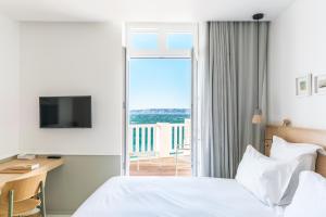 a hotel room with a bed and a desk and a balcony at Les Bords De Mer in Marseille