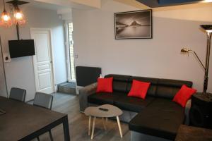 uma sala de estar com um sofá castanho e almofadas vermelhas em A 20 kms du Mont St Michel, Charme à la campagne em Saint-Senier-de-Beuvron