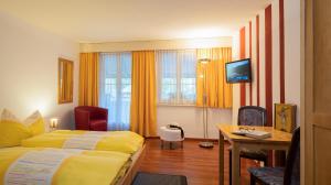 una camera d'albergo con letto, scrivania e TV di Hotel Garni Bären Rüegsau a Ruegsau