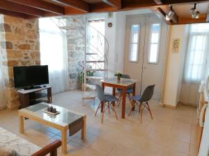 un soggiorno con tavolo, sedie e TV di THEOS APARTMENTS a Calimno (Kalymnos)