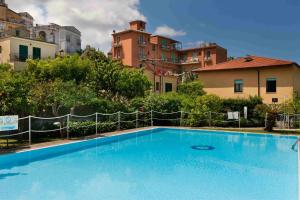 een groot blauw zwembad met gebouwen op de achtergrond bij Hotel Girasole in Sorrento