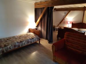 ein Schlafzimmer mit einem Bett und einem Stuhl in einem Zimmer in der Unterkunft Logement à la ferme in Hangest-en-Santerre