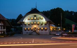 een groot gebouw met 's nachts verlichting bij Hotel Garni Bären Rüegsau in Ruegsau