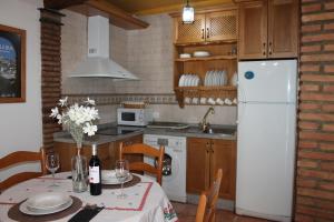 a kitchen with a table and a white refrigerator at Apartamento Rurales Rosendo: La Zajareña in Capileira