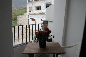 uma mesa com um vaso de flores numa varanda em Apartamento Rurales Rosendo: La Zajareña em Capileira