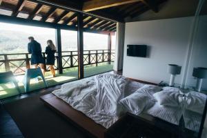 a bedroom with a bed and a couple walking on a balcony at Quinta Cercas da Costa in Vieira do Minho +79 photos
