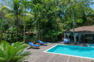 a backyard with a swimming pool and chairs and a house at Etnia Casa Hotel in Trancoso