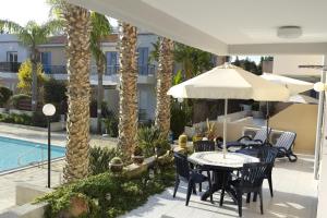 een patio met tafels en parasols en een zwembad bij Maya's Apartment - Complimentary Paphos Airport Transport in Paphos City