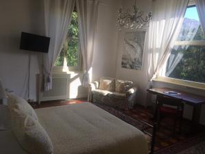 a bedroom with a bed and a chair and windows at Villa del Cigno in Lecco