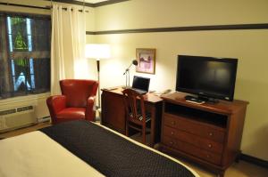 a hotel room with a bed and a desk with a television at Hôtel Le Francis in New Richmond
