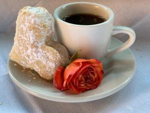 eine Tasse Kaffee und einen Donut und eine Rose auf einem Teller in der Unterkunft The Country Inn in Stone Ridge