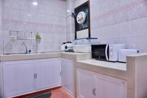 a white kitchen with a sink and a microwave at พี่จ๋า เฮ้าส์ P'Ja House in Ban Kohong
