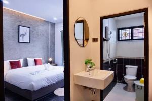 a bedroom with a bed and a sink and a mirror at พี่จ๋า เฮ้าส์ P'Ja House in Ban Kohong
