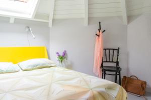 1 dormitorio con 1 cama con cabecero amarillo y silla en Unique 3 floor apartment at Westerpark, en Ámsterdam